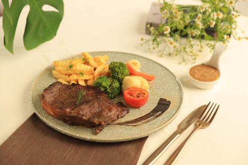 a plate of steak and vegetables on a table at WE HOTEL RIVERFRONT in Bang Su