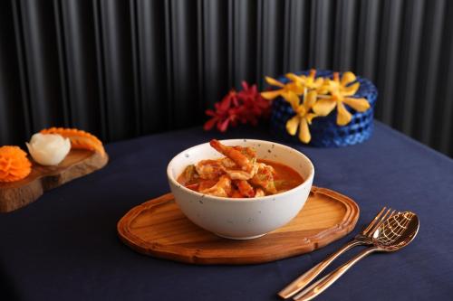 a bowl of food sitting on a table with a plate at WE HOTEL RIVERFRONT in Bang Su