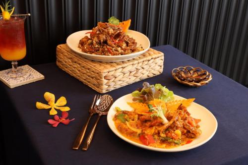 a table with two plates of food and a drink at WE HOTEL RIVERFRONT in Bang Su