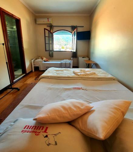 a room with two beds with pillows and a window at Pousada Tuiuiu in Angra dos Reis