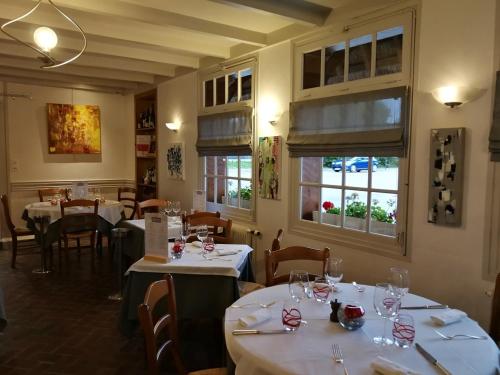 un restaurant avec des tables et des chaises blanches et des fenêtres dans l'établissement Auberge du Vieux Tour Le Manoir, à Canapville