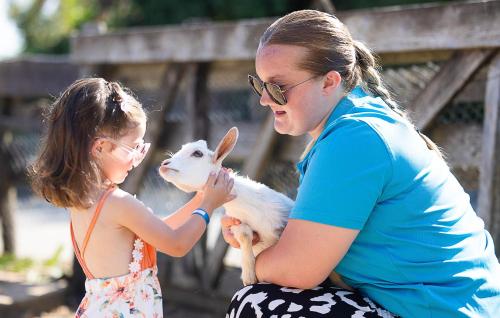 une femme tenant une petite fille tenant une chèvre dans l'établissement Camping Paradis La Grand'Métairie, à Saint-Hilaire-la-Forêt