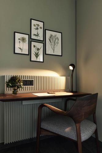 a desk with a chair and some pictures on the wall at Parkhotel Gütersloh in Gütersloh