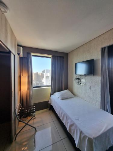 a hotel room with a bed and a large window at Savassi Tower Cobertura in Belo Horizonte