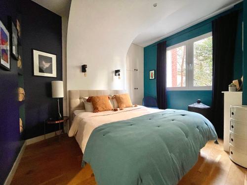 une chambre avec un grand lit aux murs bleus dans l'établissement Superbe Appartement côté Jardin, à Paris
