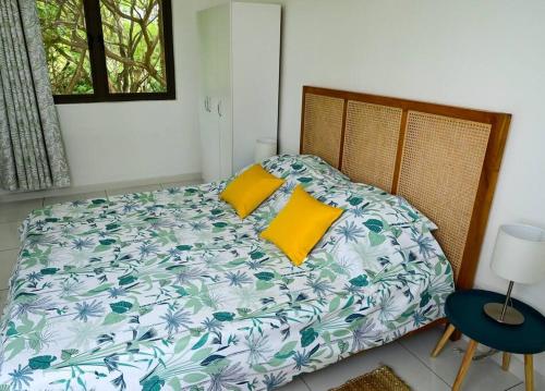 een bed met 2 gele kussens in een slaapkamer bij Apt au calme proche mer terrasse in Flic-en-Flac