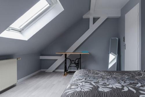 a bedroom with a bed and a table in a attic at Gîte spacieux, lumineux et très cosy in Lautenbach