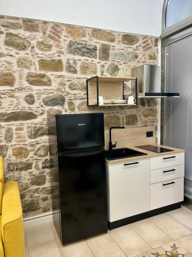 a kitchen with a black refrigerator and a stone wall at THE PALACE B&B and Apartments in Santo Stefano di Camastra