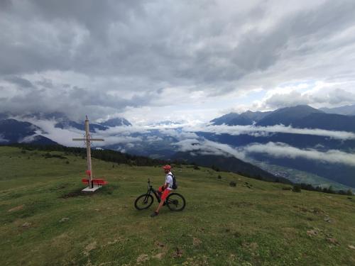 a person with a bike on a hill next to a cross at Carina's Apartment in Obsteig