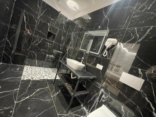 a black marble bathroom with a sink and a mirror at Hotel Panorama & Spa Elbasan in Elbasan