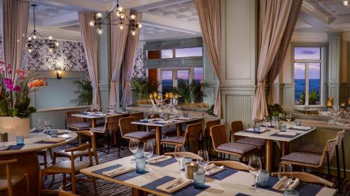 a restaurant with tables and chairs and windows at Pelican Grand Beach Resort, a Noble House Resort in Fort Lauderdale