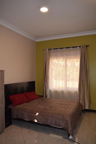 ein Schlafzimmer mit einem großen Bett mit Fenster in der Unterkunft Kyanja Luxury Suites in Kampala