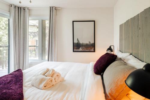 a bedroom with a bed with white sheets and purple pillows at Beautiful Condo 3-Eleven at Tremblant in Mont-Tremblant