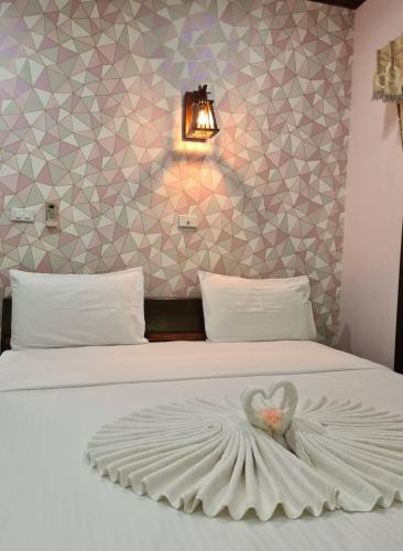 a bedroom with a white bed with a heart on it at Dhammachart RiverView in Samut Songkhram