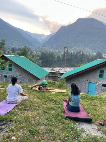 a group of three people sitting on the grass at The Satvic Retreat in Manāli
