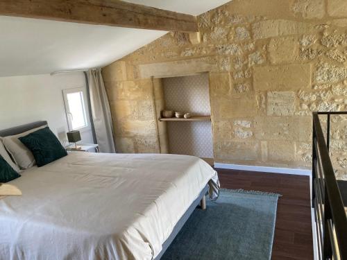 une chambre avec un lit et un mur en pierre dans l'établissement Les Agapanthes - Adult only, à Montagne