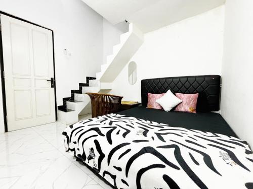 a zebra print bed in a white bedroom with stairs at Kost Harian Semarang Murah in Semarang