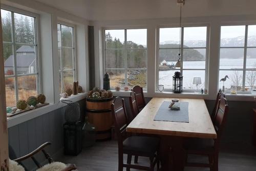 a dining room with a table and chairs and windows at Hus ved sjøen 4 soverom 10 gjester in Salsbruket