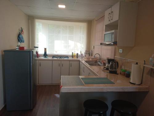 a kitchen with white cabinets and a counter with stools at Casita Independiente, Ubicada Atrás de Nuestra Casa in David