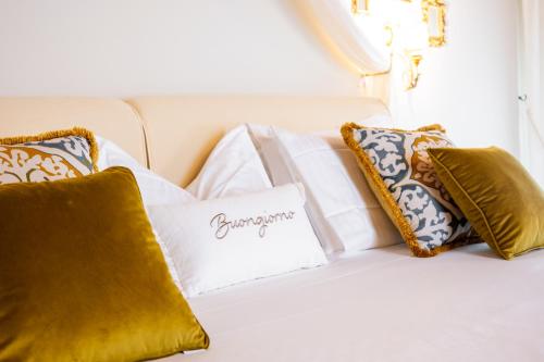 a white bed with gold pillows and a sign on it at Villa Giulia Relais & Spa in Jesolo