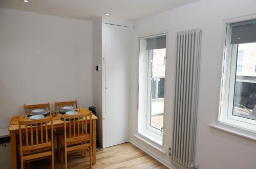 a dining room with a table and two windows at New Luxury Apartments in Central London Next to Shops, Cafes, Bars & Metro in London