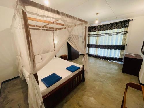 a bedroom with a canopy bed with blue pillows at Abinu"s Place in Dickwella