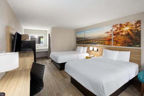 a hotel room with two beds and a flat screen tv at Days Inn by Wyndham Helen in Helen