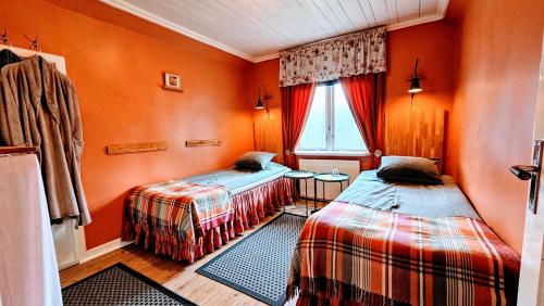 two beds in a room with orange walls at Ullaredsgården B&B Express in Ullared