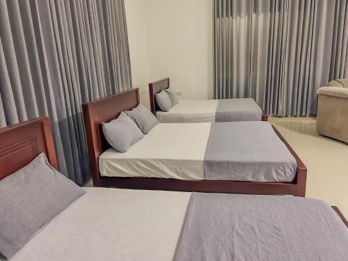 Neem safari lodge Yala في تيساماهاراما: سريرين في غرفة الفندق مع ستائر