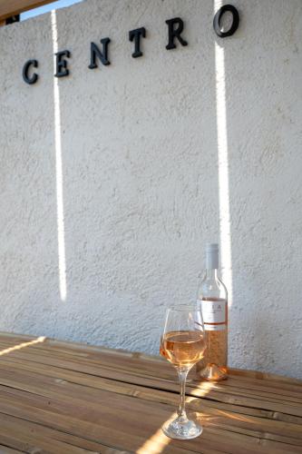a glass of wine sitting on a table with a bottle of wine at Centro Stone House in Tolo