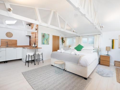 a white bedroom with a large bed and a kitchen at Bright & Airy Countryside Cabin Near Oxford, Perfect Getaway with Scenic Views - Pass the Keys in Stanton Saint John