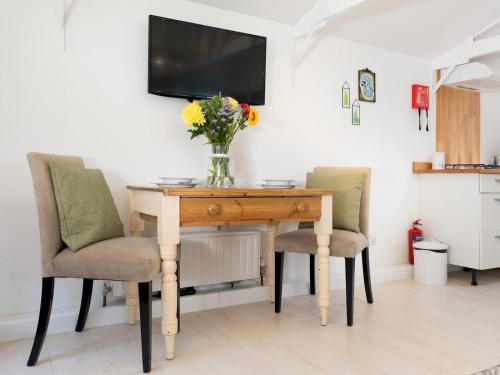 a vase of flowers on a wooden table with two chairs at Bright & Airy Countryside Cabin Near Oxford, Perfect Getaway with Scenic Views - Pass the Keys in Stanton Saint John