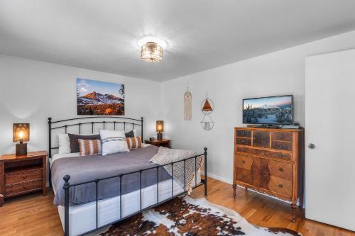 a bedroom with a bed and a dresser and a television at BEkiND Cottage in Bend