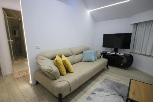 a living room with a couch with yellow and blue pillows at Metaj House in Borsh