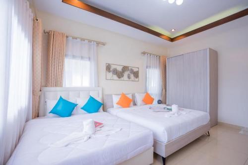 2 łóżka w pokoju z białymi i niebieskimi poduszkami w obiekcie My Sugar Pool Villa Na Jomtien w mieście Jomtien Beach