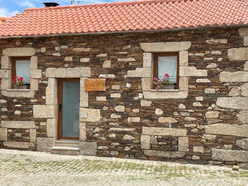 a stone building with two windows with flowers in them at Casa de Xisto Ti Lucília in Videmonte
