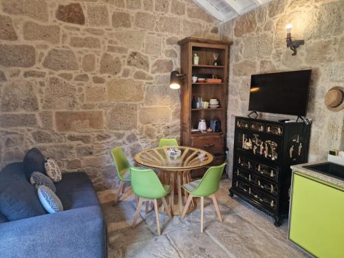 a living room with a table and chairs and a tv at Quinta do Moinho da Ínsua in Ponte de Lima