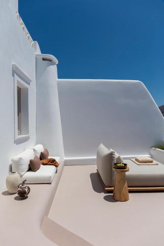 a white room with two chairs and a couch at Canaves Ena - Small Luxury Hotels of the World in Oia