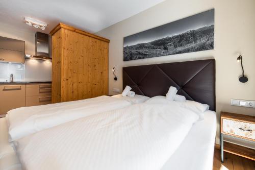 a bedroom with a large white bed and a kitchen at Wildkogel Resorts - DAS Bramberg in Bramberg am Wildkogel
