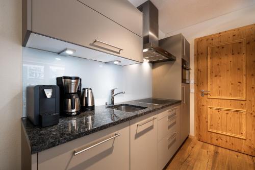 a kitchen with a sink and a wooden door at Wildkogel Resorts - DAS Bramberg in Bramberg am Wildkogel