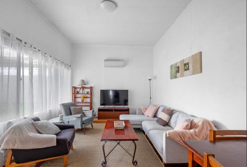 a living room with a couch and a tv at Canterbury Cottage - dog friendly - fully fenced in Wonthaggi