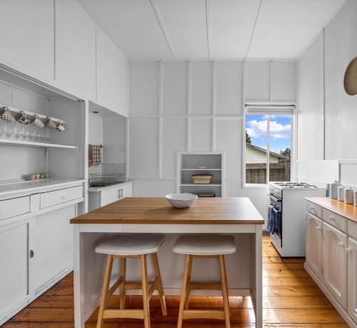 a kitchen with a wooden table and two bar stools at Canterbury Cottage - dog friendly - fully fenced in Wonthaggi
