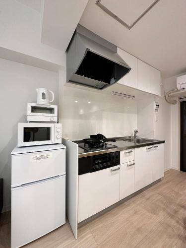 a white kitchen with a stove and a microwave at F Style Namiki by b hotel in Hiroshima
