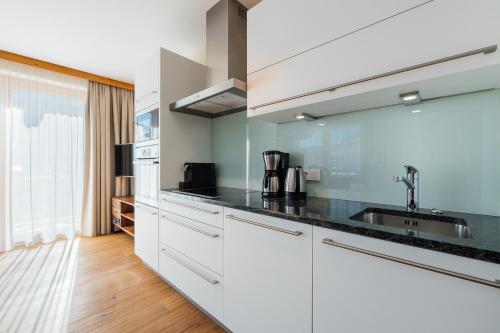 a kitchen with white cabinets and black counter tops at Wildkogel Resorts - DAS Bramberg in Bramberg am Wildkogel