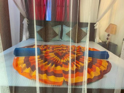 a bed with a colorful blanket on top of it at Deshan Homestay & Restaurant in Tangalle
