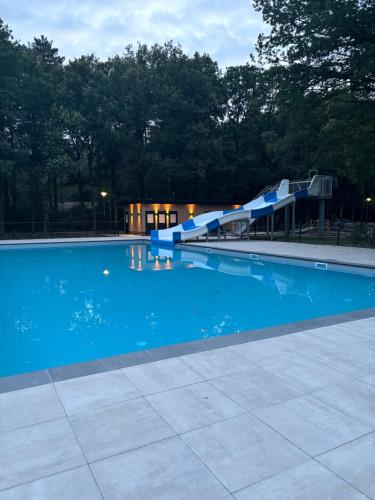 a blue swimming pool with a water slide at Chalet de kleine Eekhoorn in Lage Mierde