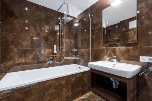 a bathroom with a bath tub and a sink at Wildkogel Resorts - DAS Bramberg in Bramberg am Wildkogel