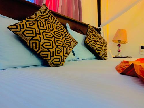 a bed with two black and white pillows on it at Deshan Homestay & Restaurant in Tangalle