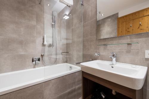 a bathroom with a sink and a shower and a bath tub at Wildkogel Resorts - DAS Bramberg in Bramberg am Wildkogel