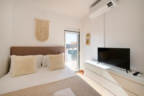 a white bedroom with a bed and a flat screen tv at Lisbon Lodge 2# in Lisbon